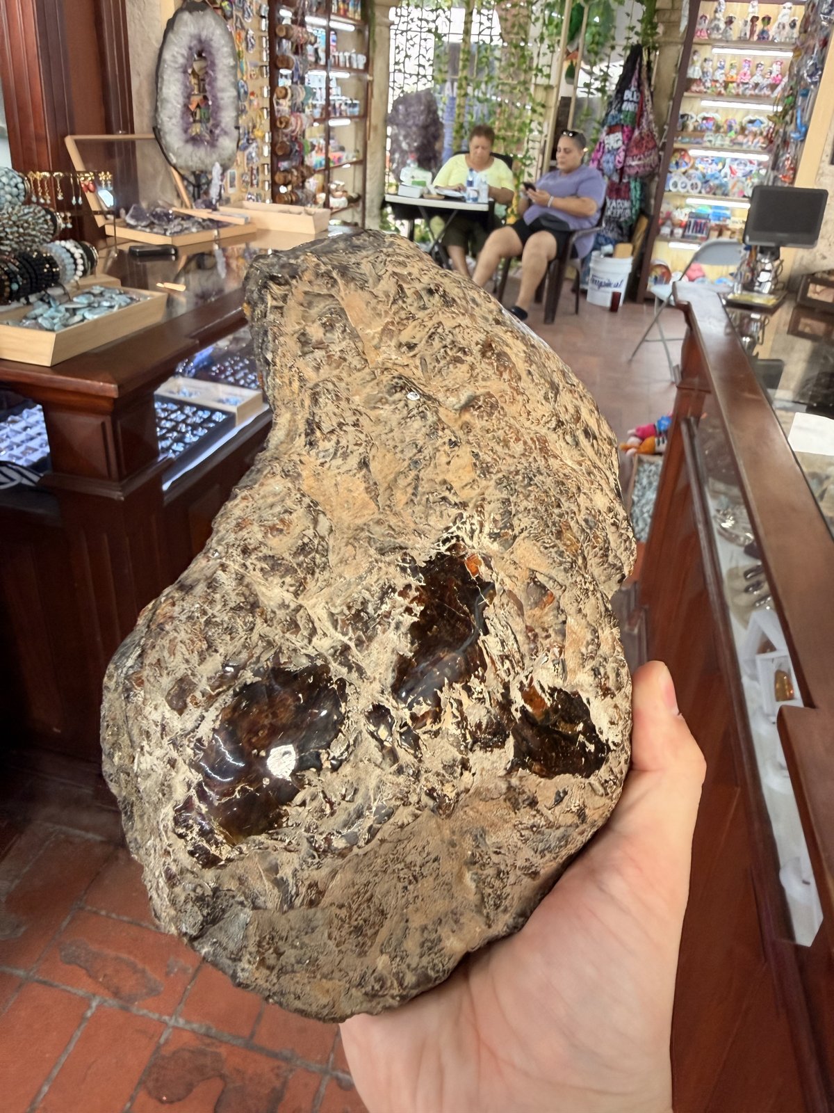 Roca de ámbar en bruto sostenida con una mano, con ventanas pulidas que dejan ver el interior color miel