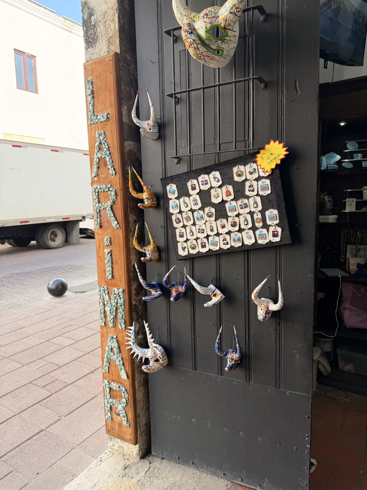 Cartel de LARIMAR hecho con piedras de larimar y máscaras de diablo colgadas en la puerta