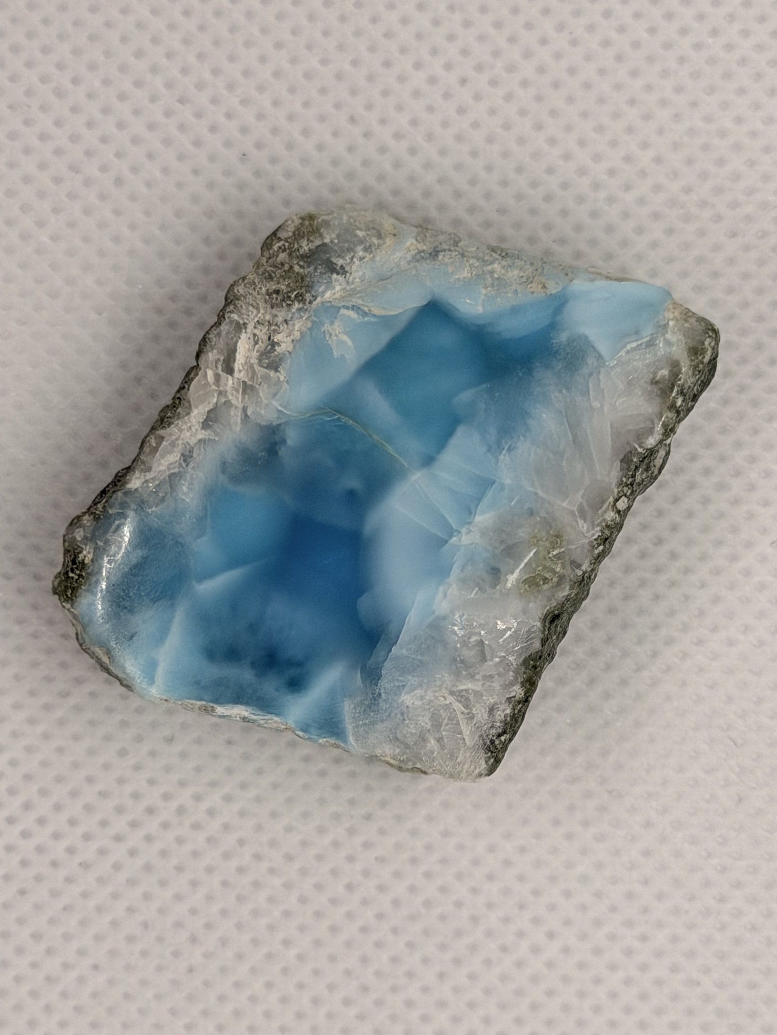 A rough larimar stone, sea-blue patterns spreading across white crystal
