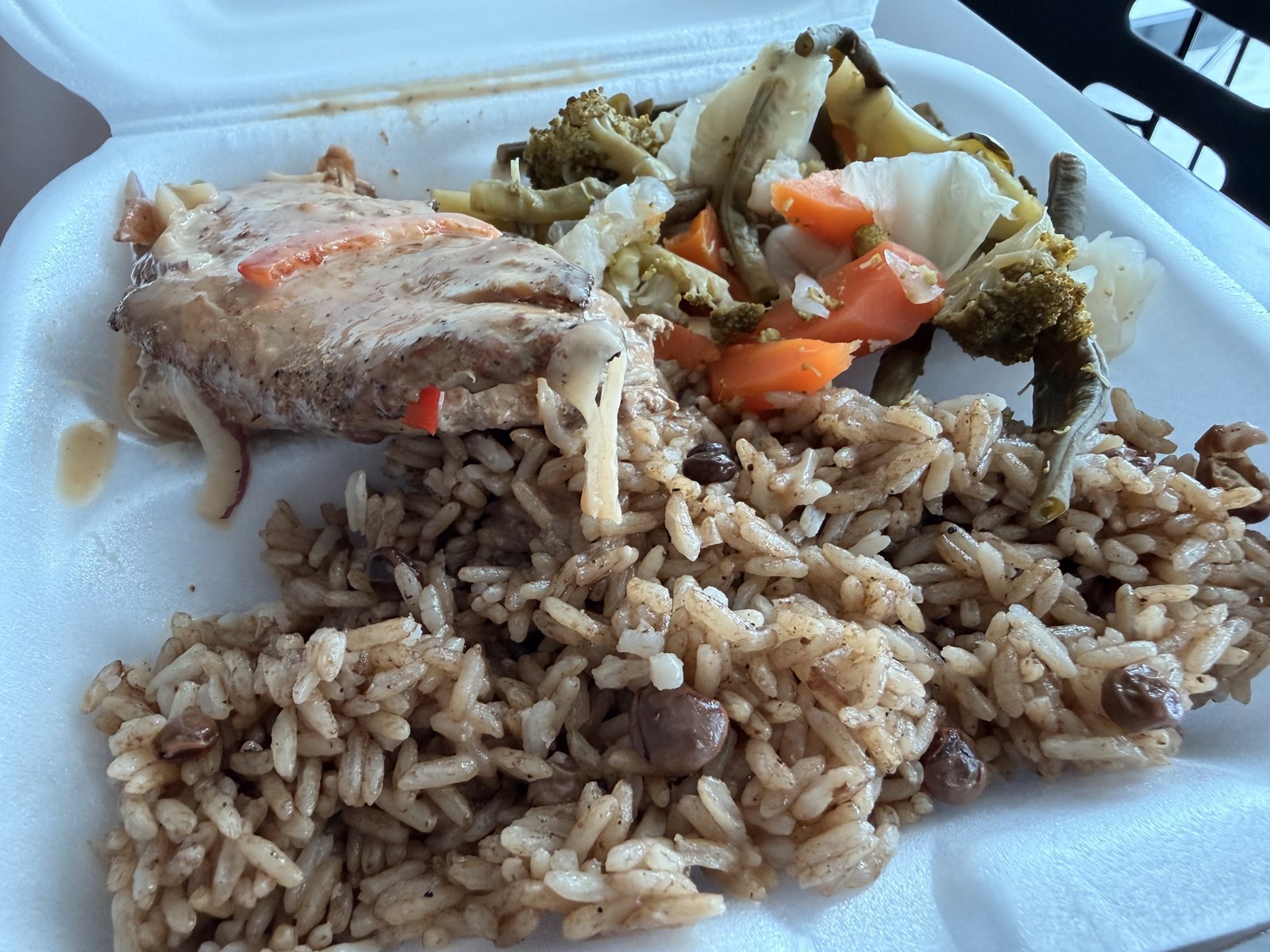 A takeout box of moro de guandules with stewed chicken and vegetables